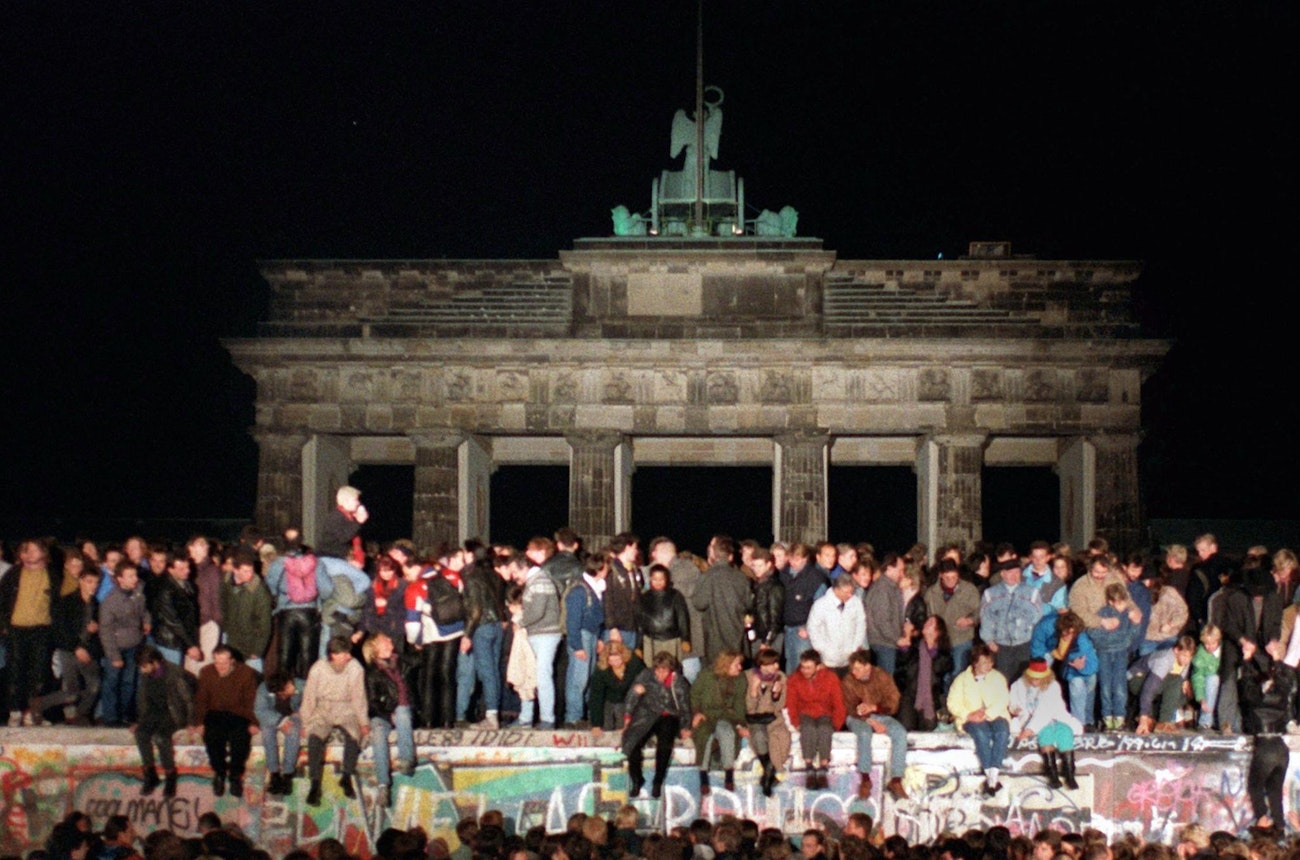 https://bestattungsportal-production.imgix.net/product_images/3349/das-ende-der-ddr-mauerfall-100~2400x1350.jpeg?ixlib=php-3.3.1